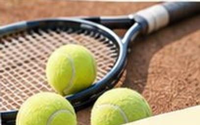 Bola tenis di atas raket di lapangan tanah liat